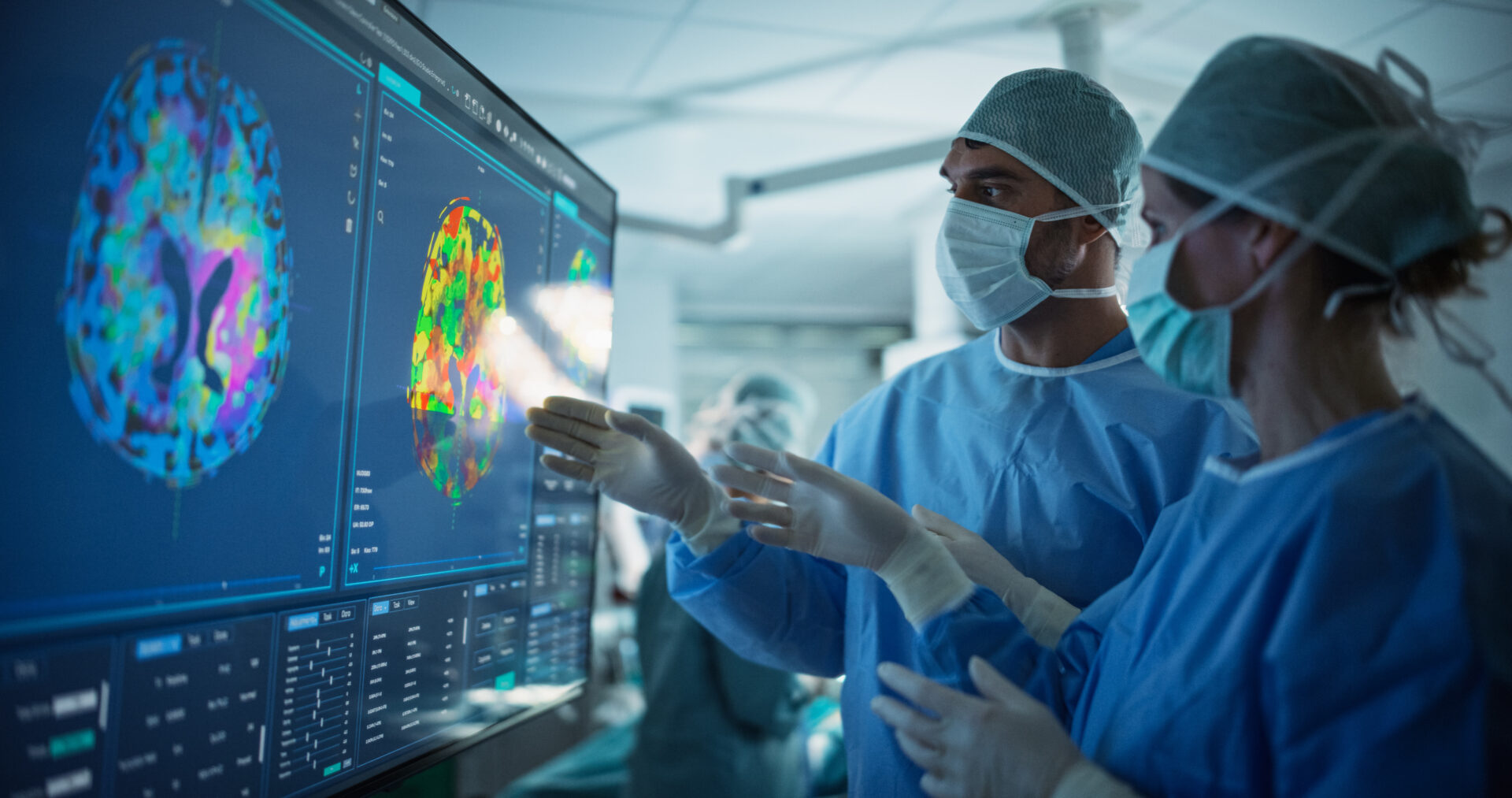 Before Beginning the Surgery, Female Lead Surgeon and an Assistant Looking at Detailed Brain PET Scans on a Large Computer Screen, Making Key Decisions Together with the Surgical Team